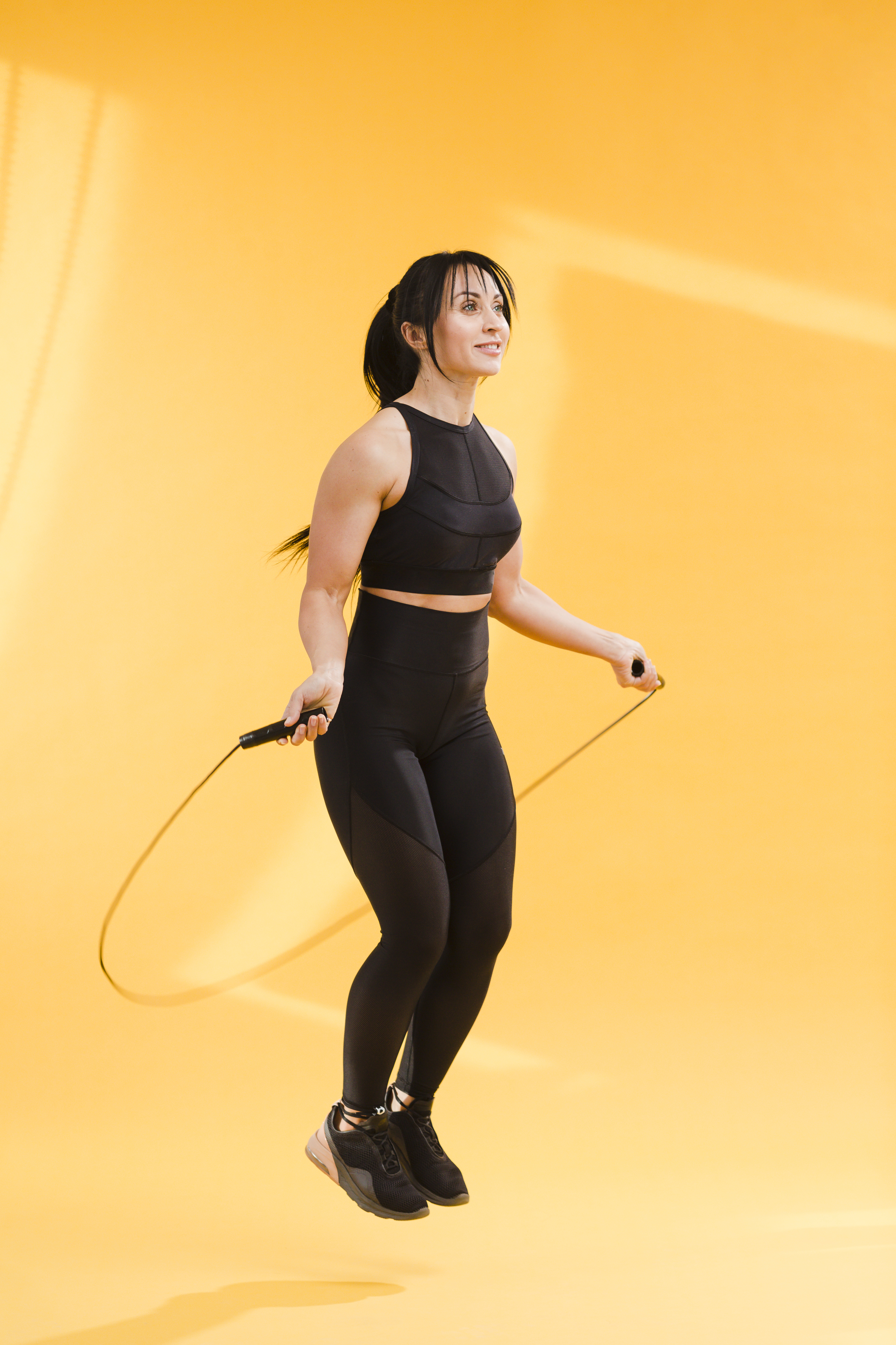 side-view-athletic-woman-gym-outfit-jumping-rope