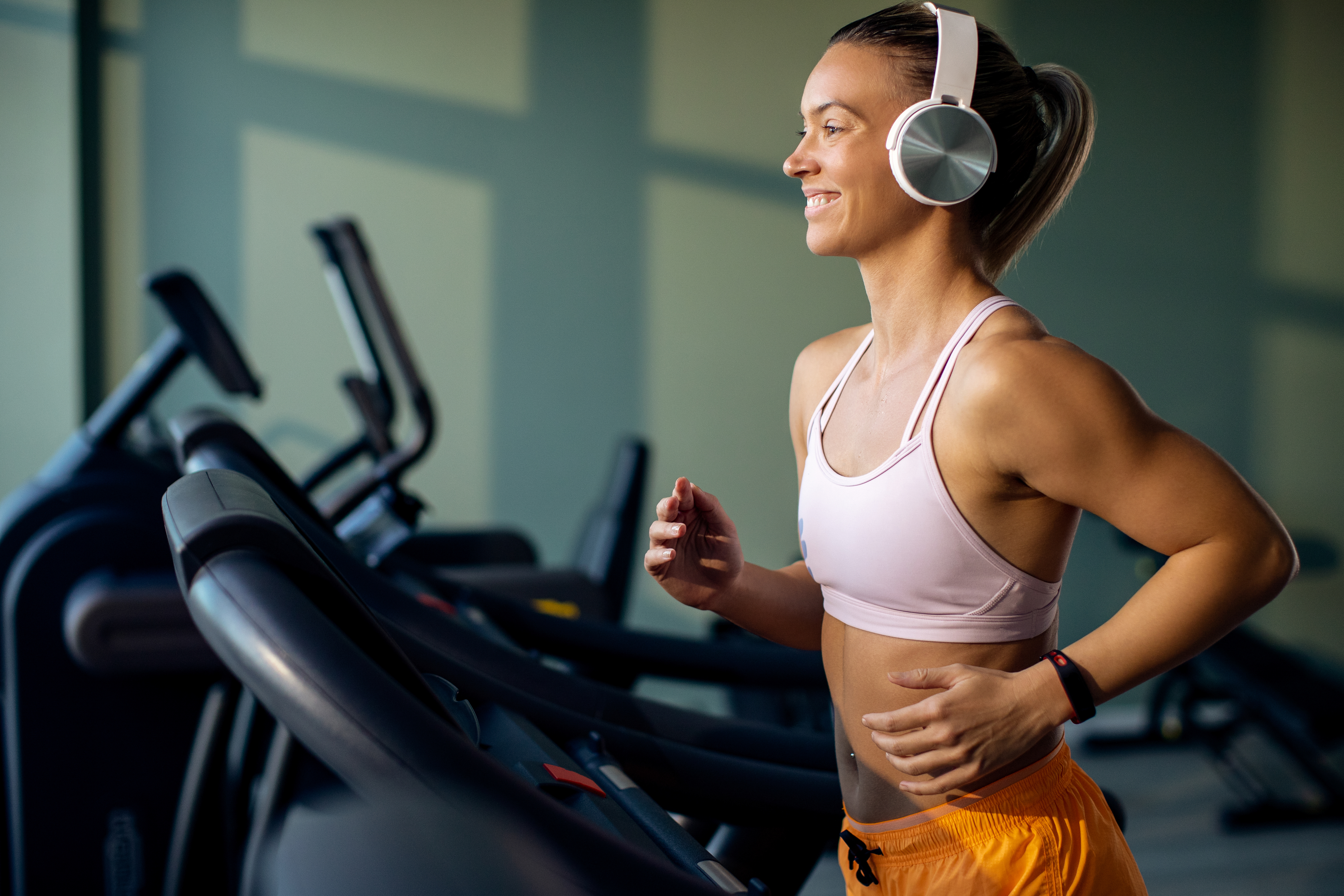 Happy female athlete running on treadmill in a gym.